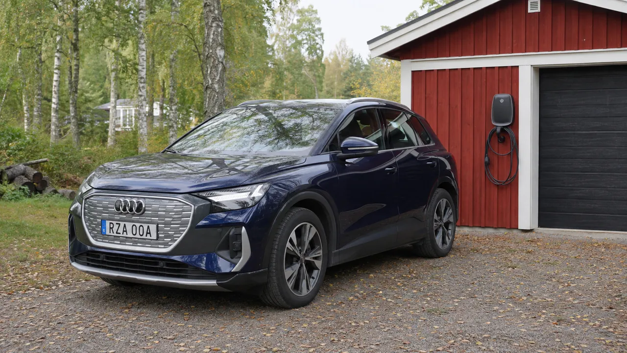 Audi Q4 e-tron står vid en laddbox på ett rödmålat garage.