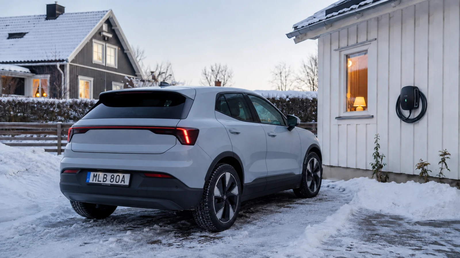 Elbil parkerad vid en laddbox utanför en svensk villa på vintern