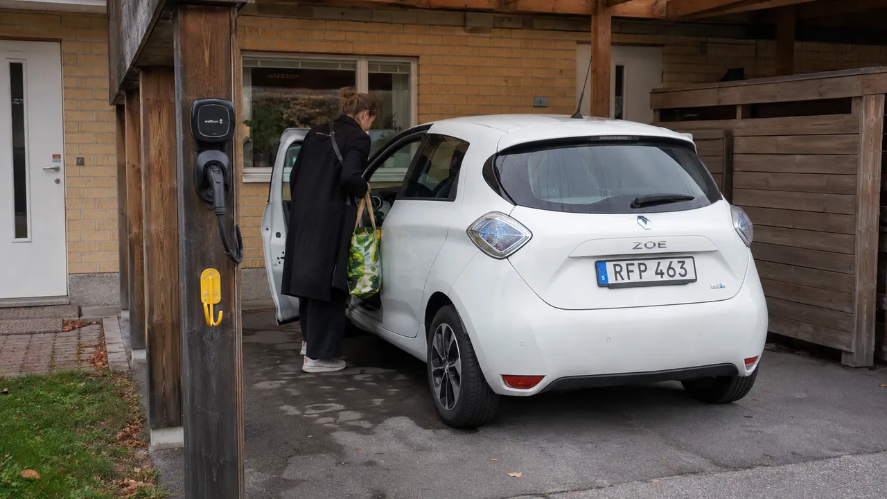 Liten laddbox med fast kabel i en radhuscarport bredvid en parkerad elbil